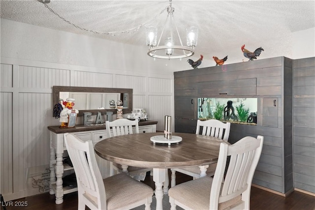 3008 Soledad Dr, Laughlin, NV 89029 - dining area with a chandelier, a decorative wall, wood finished floors, a textured ceiling, and a wainscoted wall