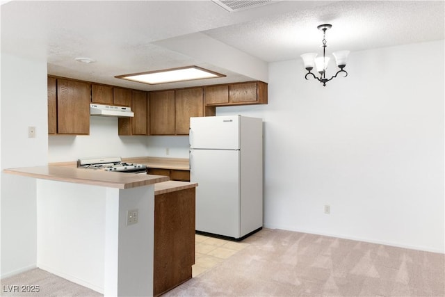 3740 Desert Marina Dr Unit 2, Laughlin, NV 89029 - kitchen featuring white appliances, under cabinet range hood, a peninsula, and brown cabinetry