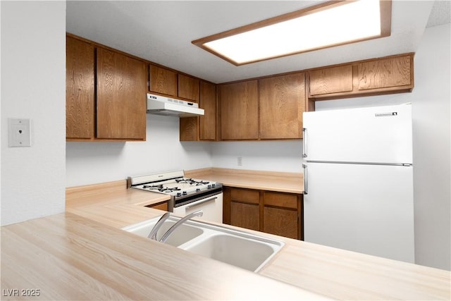 3740 Desert Marina Dr Unit 2, Laughlin, NV 89029 - kitchen with white appliances, under cabinet range hood, a sink, brown cabinetry, and light countertops