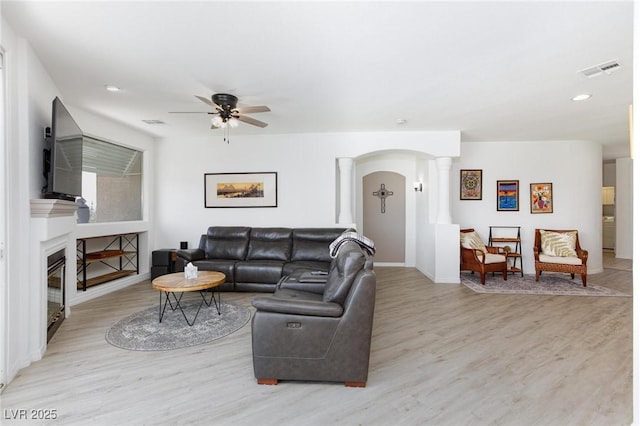 9112 Vista Greens Way Unit 204, Las Vegas, NV 89134 - living area featuring ornate columns, light wood-type flooring, ceiling fan, a glass covered fireplace, and arched walkways