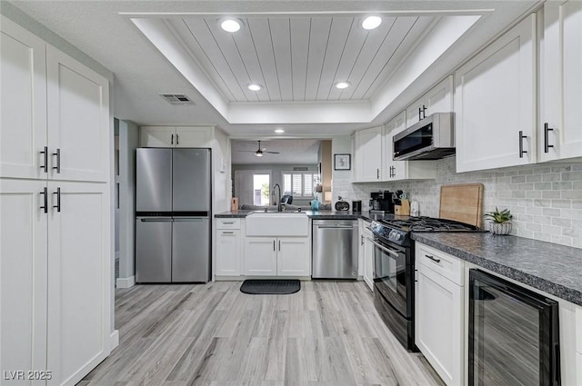 450 Intrepid Ct, Boulder City, NV 89005 - kitchen with appliances with stainless steel finishes, beverage cooler, a raised ceiling, dark countertops, and recessed lighting