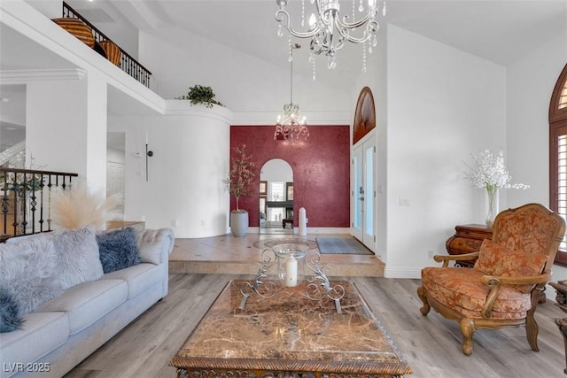4108 Royal Scots Ave, Las Vegas, NV 89141 - living room featuring high vaulted ceiling, a chandelier, arched walkways, wood finished floors, and healthy amount of natural light