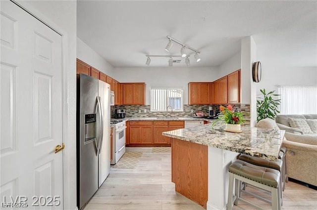 6320 Desert Leaf St Unit 101, North Las Vegas, NV 89081 - kitchen with white appliances, open floor plan, light wood-style flooring, a sink, and a breakfast bar