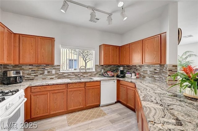 6320 Desert Leaf St Unit 101, North Las Vegas, NV 89081 - kitchen featuring white appliances, a sink, light stone counters, light wood-style flooring, and tasteful backsplash