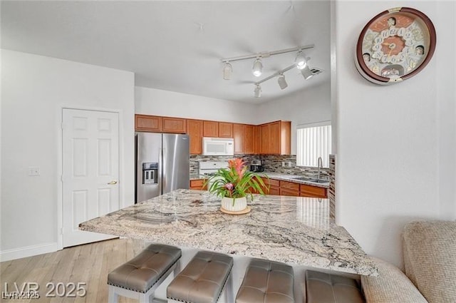 6320 Desert Leaf St Unit 101, North Las Vegas, NV 89081 - kitchen with stainless steel fridge, white microwave, a sink, a breakfast bar area, and light stone counters