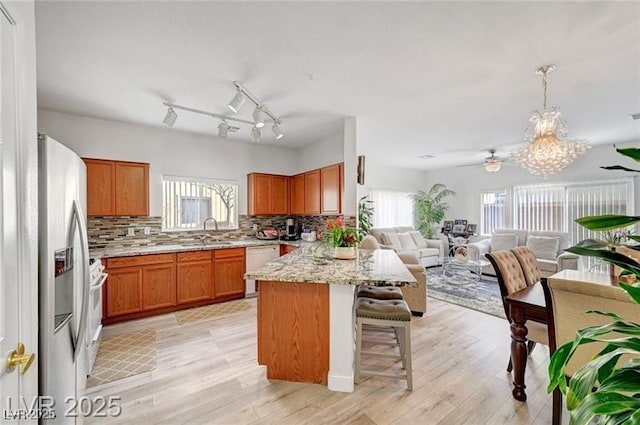 6320 Desert Leaf St Unit 101, North Las Vegas, NV 89081 - kitchen with white appliances, a sink, open floor plan, brown cabinetry, and a peninsula
