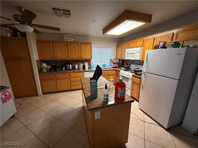 1749 Green Apple Way, Las Vegas, NV 89142 - kitchen with white appliances, light tile patterned floors, ceiling fan, backsplash, and a kitchen island