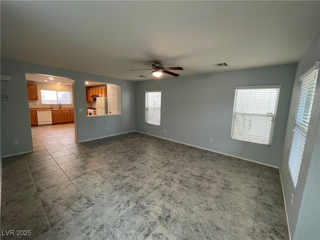 4749 Golden Shimmer Ave, Las Vegas, NV 89139 - unfurnished living room featuring a ceiling fan, plenty of natural light, a sink, and baseboards