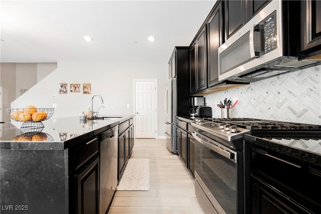 7002 Fossil Rim St, North Las Vegas, NV 89084 - kitchen with stainless steel appliances, a sink, dark cabinetry, tasteful backsplash, and an island with sink