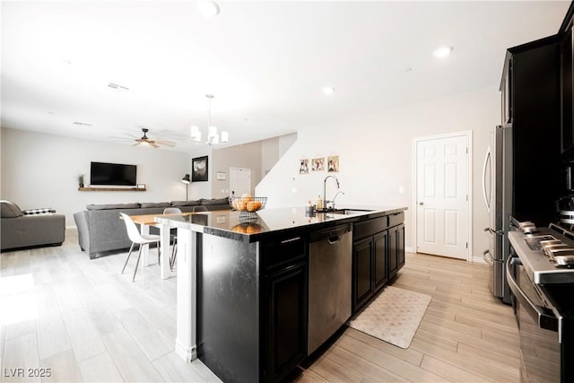 7002 Fossil Rim St, North Las Vegas, NV 89084 - kitchen with stainless steel appliances, a sink, dark cabinets, a kitchen island with sink, and open floor plan