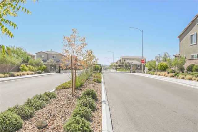 7002 Fossil Rim St, North Las Vegas, NV 89084 - view of asphalt road featuring street lighting, traffic signs, a gate, sidewalks, and a gated entry