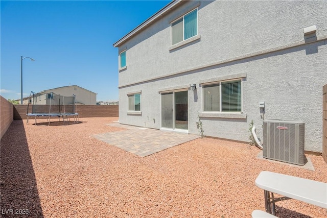7002 Fossil Rim St, North Las Vegas, NV 89084 - back of property featuring central AC unit, a trampoline, a fenced backyard, a patio area, and stucco siding
