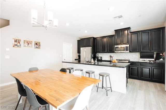 7002 Fossil Rim St, North Las Vegas, NV 89084 - kitchen with stainless steel microwave, freestanding refrigerator, an island with sink, dark countertops, and recessed lighting