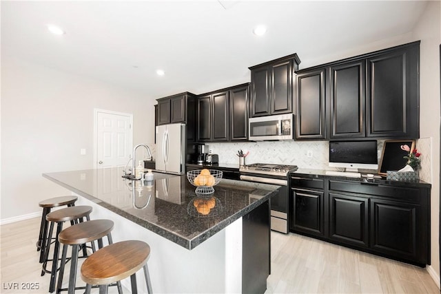 7002 Fossil Rim St, North Las Vegas, NV 89084 - kitchen featuring appliances with stainless steel finishes, a sink, dark cabinets, a kitchen bar, and light wood-style floors
