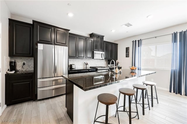 7002 Fossil Rim St, North Las Vegas, NV 89084 - kitchen featuring stainless steel appliances, light wood finished floors, an island with sink, backsplash, and recessed lighting
