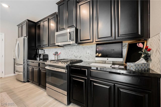 7002 Fossil Rim St, North Las Vegas, NV 89084 - kitchen featuring appliances with stainless steel finishes, dark cabinetry, decorative backsplash, and light wood finished floors