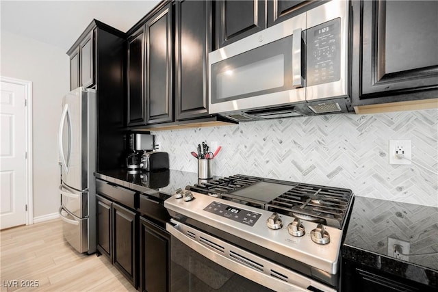 7002 Fossil Rim St, North Las Vegas, NV 89084 - kitchen with stainless steel appliances, decorative backsplash, dark cabinetry, and light wood finished floors