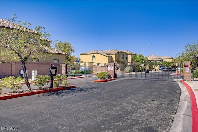 320 Point Loma Ave, North Las Vegas, NV 89031 - view of asphalt street with a gate, curbs, street lights, a gated entry, and sidewalks