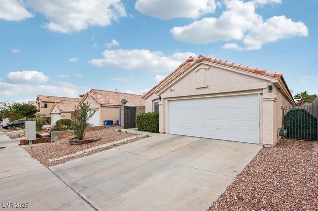 9333 Jumpin Juniper Ave, Las Vegas, NV 89129 - view of front of house featuring stucco siding, driveway, a tiled roof, and an attached garage