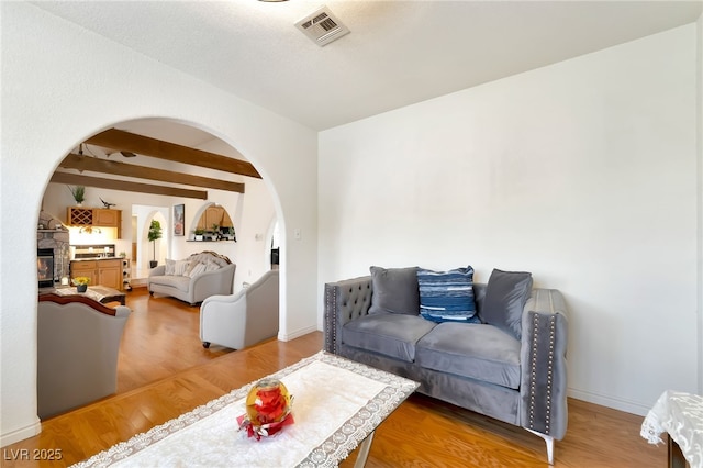 5829 W Patrick Ln, Las Vegas, NV 89118 - living room featuring arched walkways, wood finished floors, beam ceiling, a stone fireplace, and baseboards