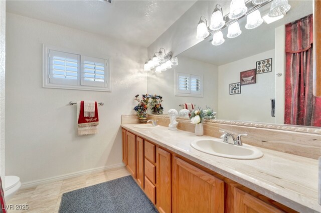 5829 W Patrick Ln, Las Vegas, NV 89118 - bathroom with double vanity, toilet, tile patterned floors, and baseboards