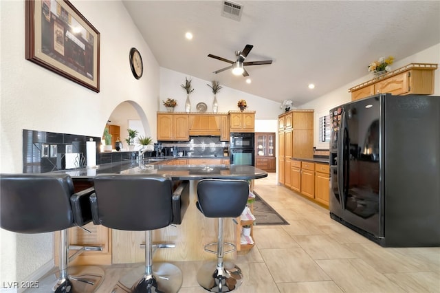 5829 W Patrick Ln, Las Vegas, NV 89118 - kitchen with black fridge, dark countertops, backsplash, lofted ceiling, and ceiling fan