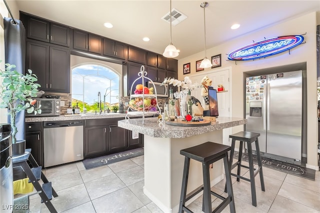 9704 Morgan Creek Ct, Las Vegas, NV 89141 - kitchen with stainless steel appliances, decorative backsplash, light countertops, light tile patterned floors, and a kitchen island
