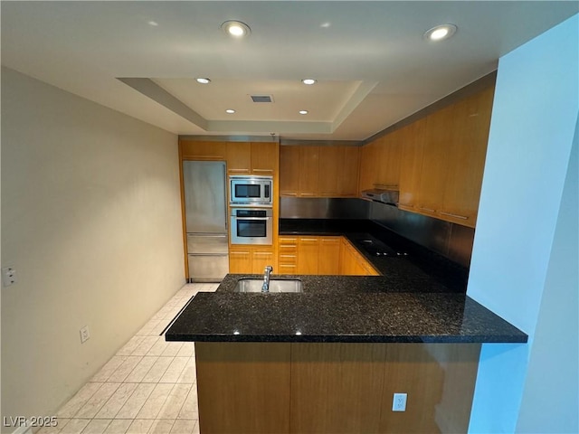 2700 Las Vegas Blvd Unit 2811, Las Vegas, NV 89109 - kitchen featuring built in appliances, a sink, a tray ceiling, a peninsula, and dark stone countertops