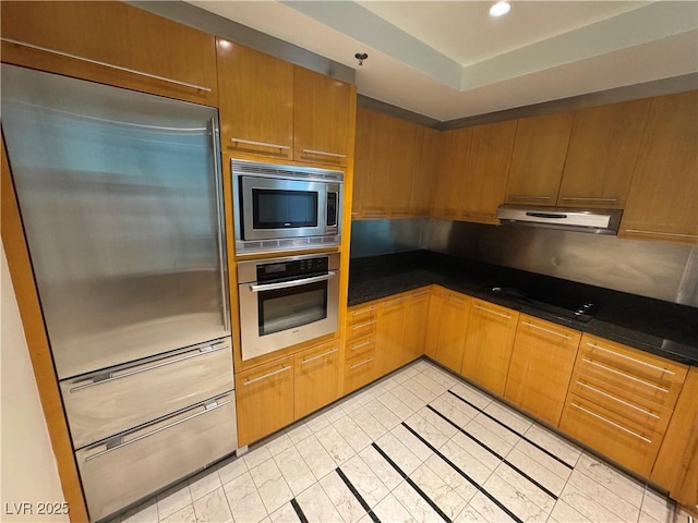 2700 Las Vegas Blvd Unit 2811, Las Vegas, NV 89109 - kitchen featuring built in appliances, dark countertops, under cabinet range hood, light tile patterned floors, and brown cabinetry