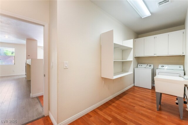 908 Cypress Gold Ct, North Las Vegas, NV 89031 - laundry area featuring washer and dryer, cabinet space, light wood finished floors, and baseboards