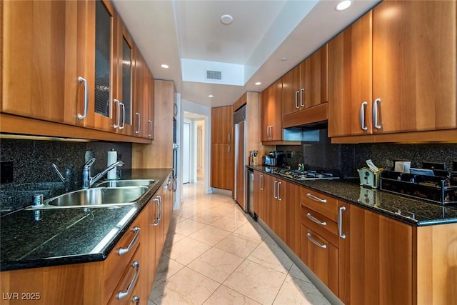 2877 Paradise Rd Unit 906, Las Vegas, NV 89109 - kitchen featuring a sink, brown cabinets, stainless steel gas stovetop, glass insert cabinets, and backsplash