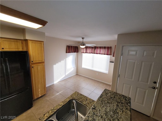 5710 E Tropicana Ave Unit 1172, Las Vegas, NV 89122 - kitchen featuring freestanding refrigerator, light tile patterned floors, a ceiling fan, baseboards, and dark stone counters