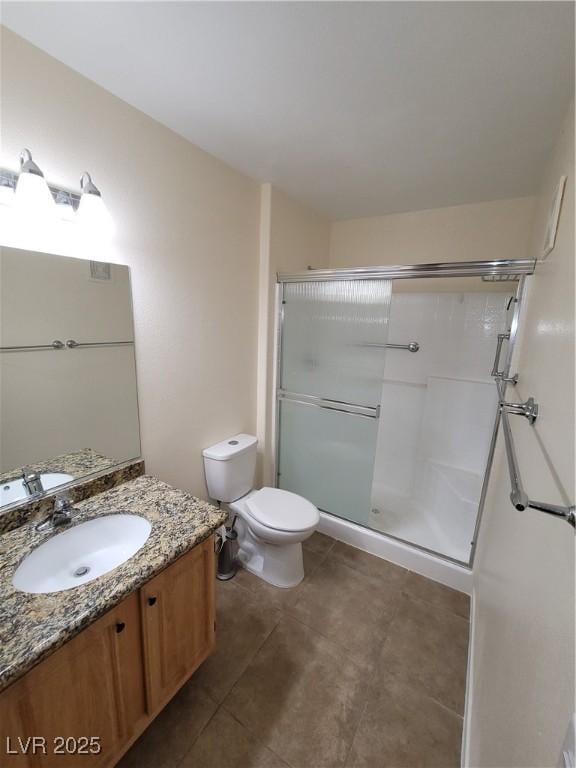 5710 E Tropicana Ave Unit 1172, Las Vegas, NV 89122 - bathroom featuring vanity, toilet, a shower with door, and tile patterned flooring