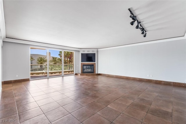 2857 Paradise Rd Unit 301, Las Vegas, NV 89109 - unfurnished living room with rail lighting, a glass covered fireplace, baseboards, crown molding, and dark tile patterned flooring