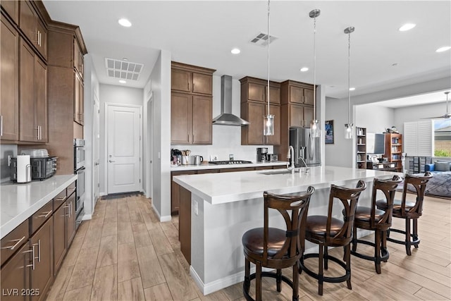 8668 Hartmont St, Las Vegas, NV 89166 - kitchen with wall chimney range hood, a sink, light wood-style floors, light countertops, and stainless steel appliances