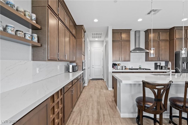 8668 Hartmont St, Las Vegas, NV 89166 - kitchen with wall chimney range hood, a sink, stainless steel fridge, gas stovetop, and a breakfast bar