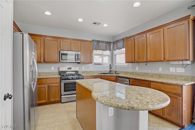 9190 Wine Cellar Ave, Las Vegas, NV 89148 - kitchen featuring appliances with stainless steel finishes, a sink, brown cabinetry, a center island, and recessed lighting