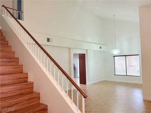 5040 Jacarilla Ln, North Las Vegas, NV 89031 - staircase featuring high vaulted ceiling, tile patterned floors, baseboards, and a chandelier