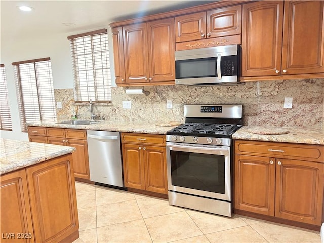 5040 Jacarilla Ln, North Las Vegas, NV 89031 - kitchen featuring appliances with stainless steel finishes, a sink, light tile patterned floors, tasteful backsplash, and light stone counters