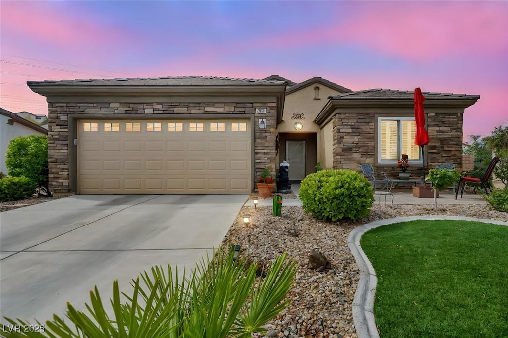 2621 Icy Moon St, Henderson, NV 89044 - view of front of home featuring concrete driveway, a garage, stucco siding, stone siding, and a tiled roof