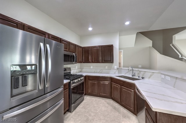 1554 Ward Frontier Ln, Henderson, NV 89002 - kitchen with stainless steel appliances, a sink, a peninsula, light stone counters, and recessed lighting