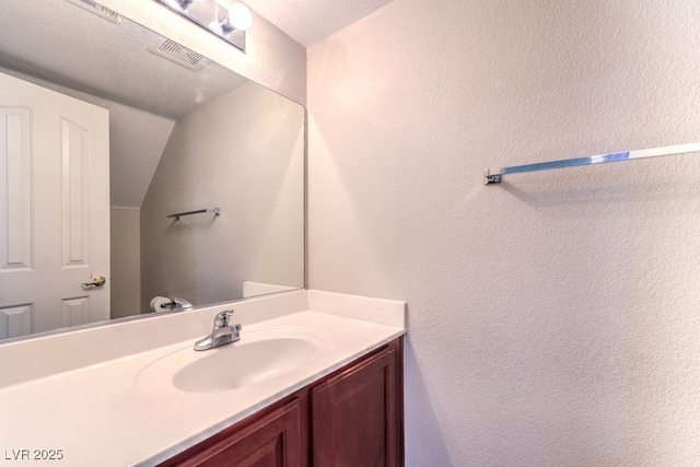 1554 Ward Frontier Ln, Henderson, NV 89002 - bathroom featuring vanity, a textured wall, and vaulted ceiling