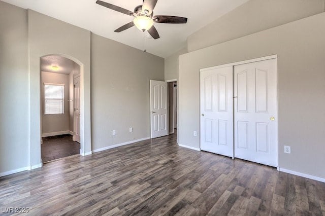 1554 Ward Frontier Ln, Henderson, NV 89002 - unfurnished bedroom featuring arched walkways, dark wood-type flooring, a closet, high vaulted ceiling, and baseboards
