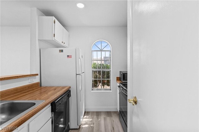 3923 Gogo Way Unit 106, Las Vegas, NV 89103 - kitchen featuring black dishwasher, white cabinets, light wood-type flooring, freestanding refrigerator, and baseboards