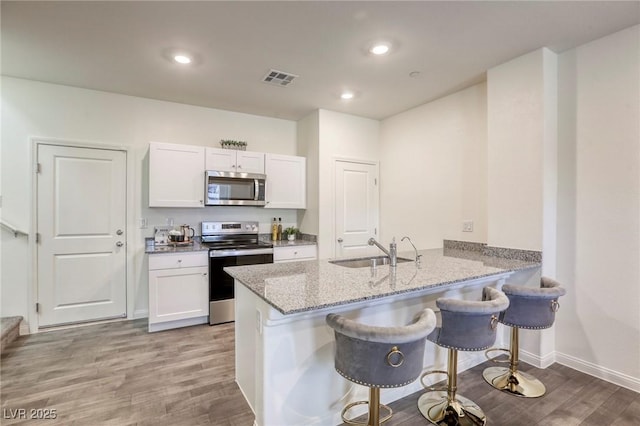 12728 Feathersong St, Henderson, NV 89044 - kitchen with appliances with stainless steel finishes, a sink, a kitchen breakfast bar, light stone countertops, and white cabinetry