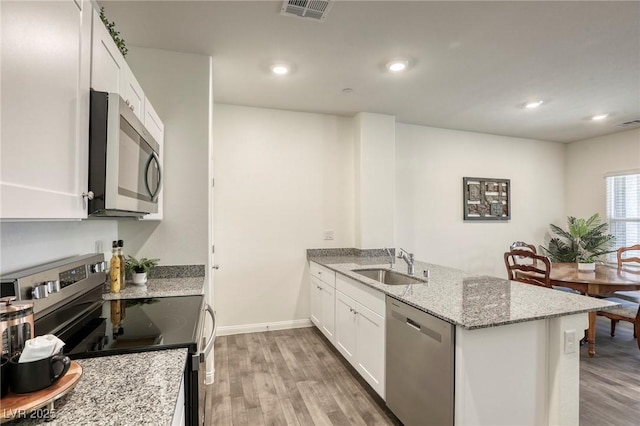 12728 Feathersong St, Henderson, NV 89044 - kitchen featuring appliances with stainless steel finishes, a sink, a peninsula, light wood finished floors, and recessed lighting