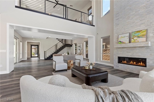 2890 Reverence Heights Ln, Las Vegas, NV 89138 - living room featuring healthy amount of natural light, a high ceiling, stairway, wood finished floors, and a stone fireplace