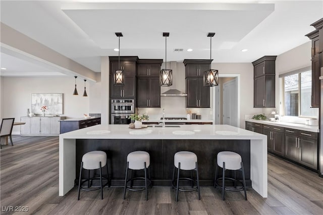 2890 Reverence Heights Ln, Las Vegas, NV 89138 - kitchen with double oven, dark wood-style flooring, a center island with sink, dark brown cabinetry, and a breakfast bar
