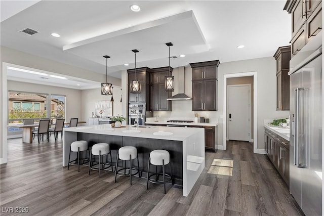 2890 Reverence Heights Ln, Las Vegas, NV 89138 - kitchen with wall chimney exhaust hood, stainless steel appliances, dark wood finished floors, light countertops, and dark brown cabinets