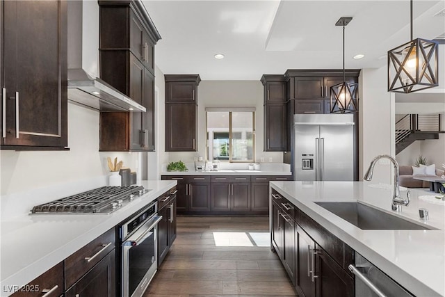 2890 Reverence Heights Ln, Las Vegas, NV 89138 - kitchen with stainless steel appliances, a sink, dark wood finished floors, dark brown cabinetry, and wall chimney range hood